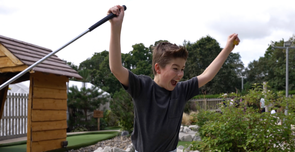 Kid celebrates with a golf club in his hand